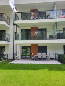 ein Apartmentgebäude mit einer Terrasse mit einem Tisch und Stühlen in der Unterkunft Plażowa Park 13 Międzywodzie in Międzywodzie