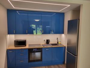 eine blaue Küche mit einer Spüle und einem Kühlschrank in der Unterkunft Plażowa Park 13 Międzywodzie in Międzywodzie + 5 Fotos