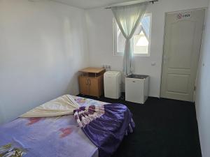 a bedroom with a bed and a table and a window at Ca la noi acasă in Costinesti