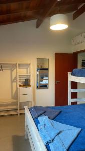 a bedroom with a bed with a blue blanket and a shelf at Casa na Praia de Santiago, próxima a Maresias! in São Sebastião
