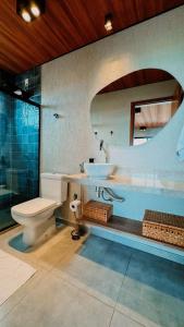 une salle de bain avec un lavabo, des toilettes et un miroir dans l'établissement Casa Vista Mar de Luxo com Serviços Inclusos, à Barra do Camaragibe