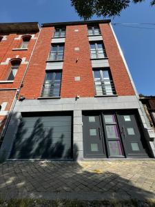 un grand bâtiment en briques avec deux portes de garage dans l'établissement L'écrin des Vennes - Liège centre, à Liège