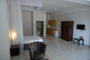 a bedroom with a bed and a chair and a couch at The Voice Hotel in Entebbe