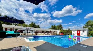 a pool at a hotel with an umbrella at Profile Deluxe Motel in Twin Mountain