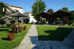 a house with a lawn with chairs and an umbrella at Ammos Kalamitsi in Kalamitsi