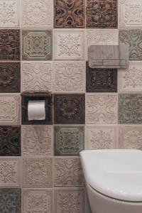 a bathroom with a toilet and a tiled wall at Lindens apartments with AC and view to central square in Panevėžys +23 photos