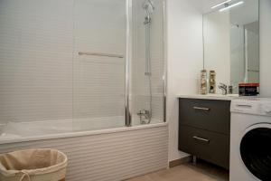 a bathroom with a tub and a sink and a washing machine at Sete, Thau Indigo B402 in Sète +17 photos