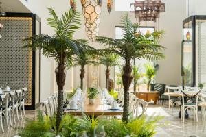 a restaurant with palm trees and tables and chairs at TUI BLUE Tuy Hoa - Wellness & Retreat Hotel in Tuy Hoa
