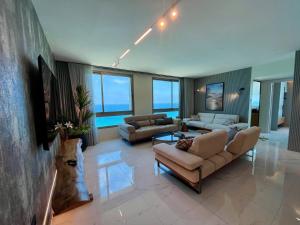 a large living room with couches and tables and windows at C Tower Apartments in Netanya