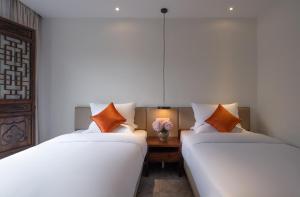 two beds sitting next to each other in a room at Mount Emei Heyuan Serene Residence Hot Spring Hotel in Emeishan City