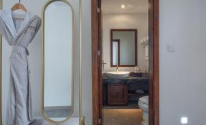 a bathroom with a mirror and a sink and a toilet at Mount Emei Heyuan Serene Residence Hot Spring Hotel in Emeishan City