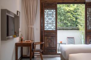 a bedroom with a bed and a window and a table at Mount Emei Heyuan Serene Residence Hot Spring Hotel in Emeishan City