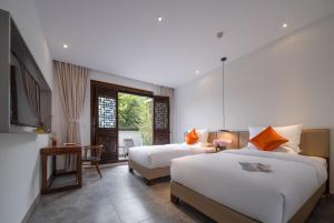 a bedroom with two beds and a table and a desk at Mount Emei Heyuan Serene Residence Hot Spring Hotel in Emeishan City