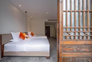 a bedroom with a white bed and a wooden door at Mount Emei Heyuan Serene Residence Hot Spring Hotel in Emeishan City