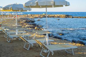 a group of tables and umbrellas on a beach at Pietrablu Resort & Spa - CDSHotels in Polignano a Mare