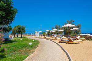 a row of lounge chairs and umbrellas on a beach at Pietrablu Resort & Spa - CDSHotels in Polignano a Mare