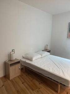 ein weißes Schlafzimmer mit einem Bett und einem Nachttisch in der Unterkunft St Cyprien superbe maison de village in Saint-Cyprien