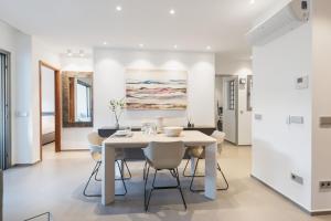 a white dining room with a white table and chairs at Agora 0-3 DELUXE 1B in Palm-mar