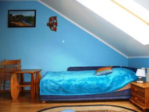 sypialnia z łóżkiem z niebieską ścianą w obiekcie Pokoje Gościnne Na Skraju Lasu w mieście Kamieniec Ząbkowicki