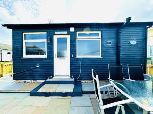 a blue house with a white door and two chairs at Warren Cottage in Bridlington