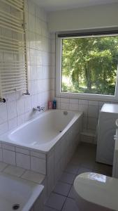 a white bathroom with a tub and a window at Paula - Bergheim-Köln Wohlfühlapartment in Bergheim
