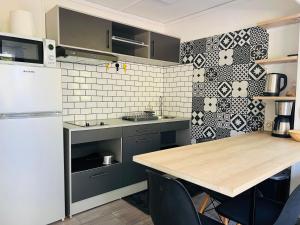 une cuisine avec une table et un réfrigérateur blanc dans l'établissement Studio Leskal centre Cilaos, à Cilaos