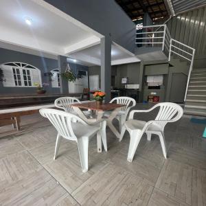 a dining room with a table and white chairs at Hope Hostel Praia do Morro in Guarapari