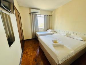 two beds in a hotel room with a window at Libero Hotel in São João da Boa Vista