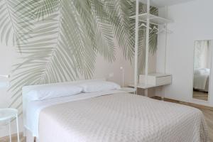 Un dormitorio con una cama blanca y un mural de palmeras. en Relais del Parco Verde e Relais del Parco Rosso, en LʼAquila