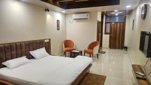 a bedroom with a bed and chairs and a tv at The Rampal's Ganga Panoramic in Rishīkesh