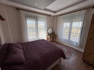 a bedroom with a bed and two large windows at GREEN VALLEY House in Avanos +59 photos