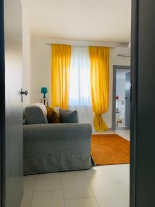 a living room with a couch and yellow curtains at Dimora Paesana in Alberobello