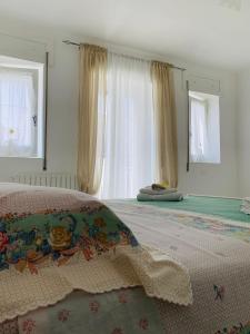 a bedroom with a bed and two windows with curtains at Dimora Paesana in Alberobello