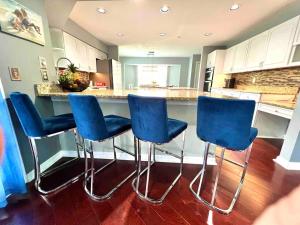 a kitchen with four blue bar stools in front of a counter at Wellington Pool House With Spa and Putting Green in Wellington