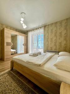 a large bed in a bedroom with a large window at ApartPoltava НОВИЙ будинок, в самому ЦЕНТРІ 2-ОКРЕМІ кімнати, ПАНОРАМНИЙ БАЛКОН in Poltava