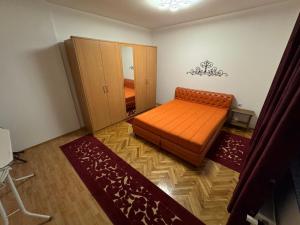 a bedroom with an orange bed and two rugs at ASKonak Apartman Novi Pazar Centar in Novi Pazar