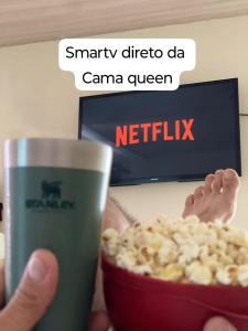 a person holding a cup of popcorn and a bowl of popcorn at Flat na área central com AR-garagem-wifi-confortável in Governador Valadares