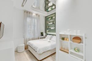 - une chambre blanche avec un lit et des étagères dans l'établissement Le Confidentiel - Bastille, à Paris