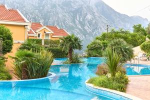 a pool with palm trees and a mountain in the background at Green Hill 2 Apartments in Gornji Orahovac