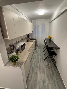 a kitchen with white cabinets and a table with chairs at Apartament 2 Cam Cetate in Alba Iulia