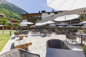 an outdoor patio with tables and chairs and umbrellas at Alpenhotel Montafon & SPA in Schruns