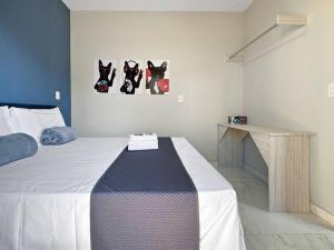 Schlafzimmer mit einem Bett mit einem Tisch und Bildern an der Wand in der Unterkunft Espaçoso Apartamento com Churrasqueira Expo Imig in São Paulo