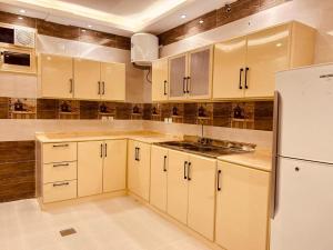 a kitchen with white cabinets and a white refrigerator at الفرعا للوحدات السكنية المفروشة ابها االواديين القرعا دلغان المسقي in Ad Dhid