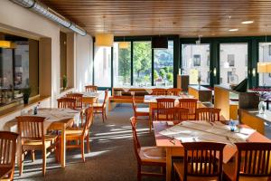 a restaurant with wooden tables and chairs and windows at JUFA Hotel Schladming in Schladming