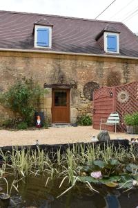 una casa con un estanque delante de un edificio en Les Girouteaux Le Fenil, en Les Eyzies-de-Tayac