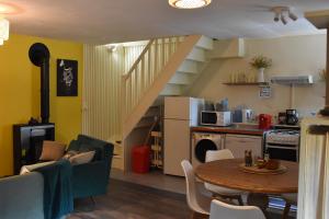 cocina y sala de estar con mesa y escalera en Les Girouteaux Le Fenil, en Les Eyzies-de-Tayac