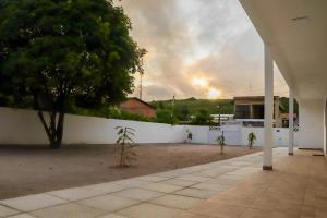 ein weißer Zaun mit einem Baum und einem Feuer im Hintergrund in der Unterkunft Águas da Barra in Maragogi