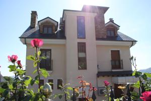 una gran casa blanca con rosas delante en Villa Mencia, en Corullón