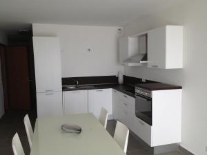 a kitchen with white cabinets and a table with chairs at Résidence Villa Tyrrenia in Macinaggio +11 photos