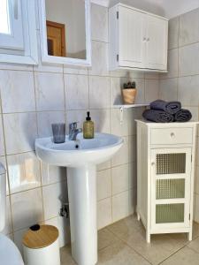Un baño con un lavabo blanco y un espejo. en The house with the arches, en Sfakerá